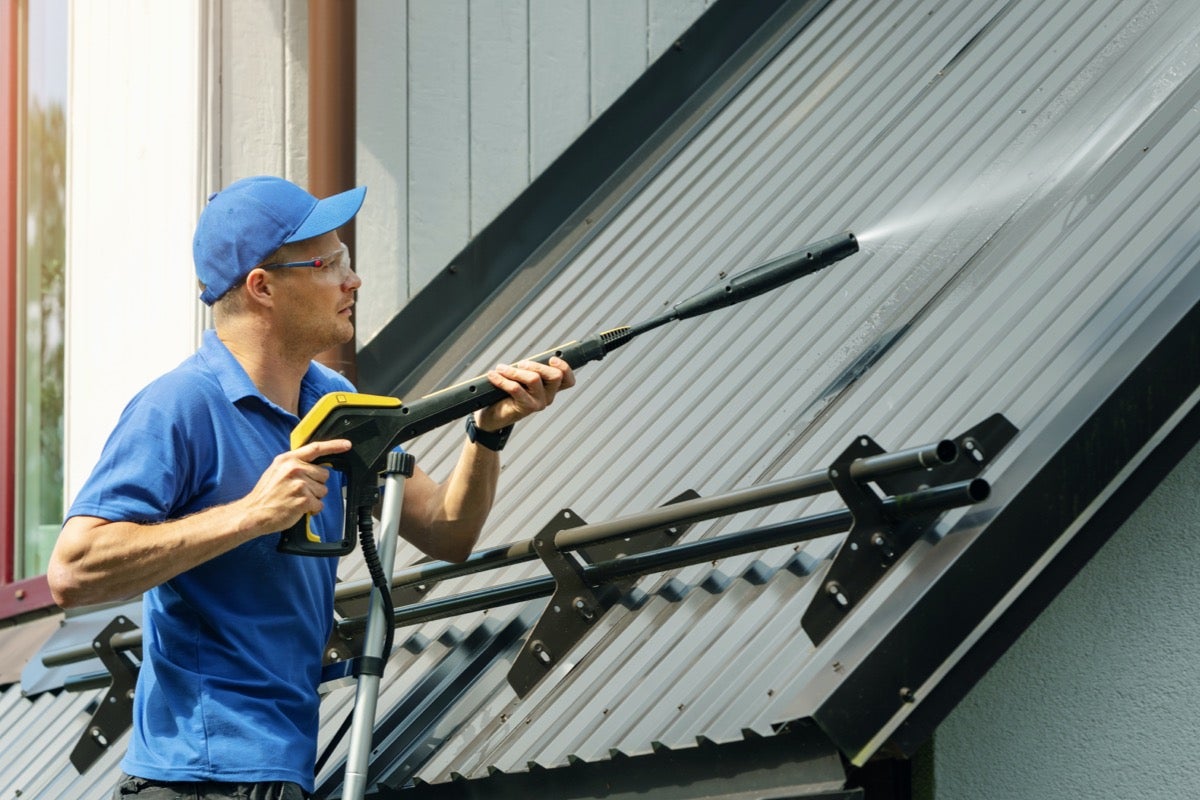 Technician pressure washing siding of a residential home in Maryland