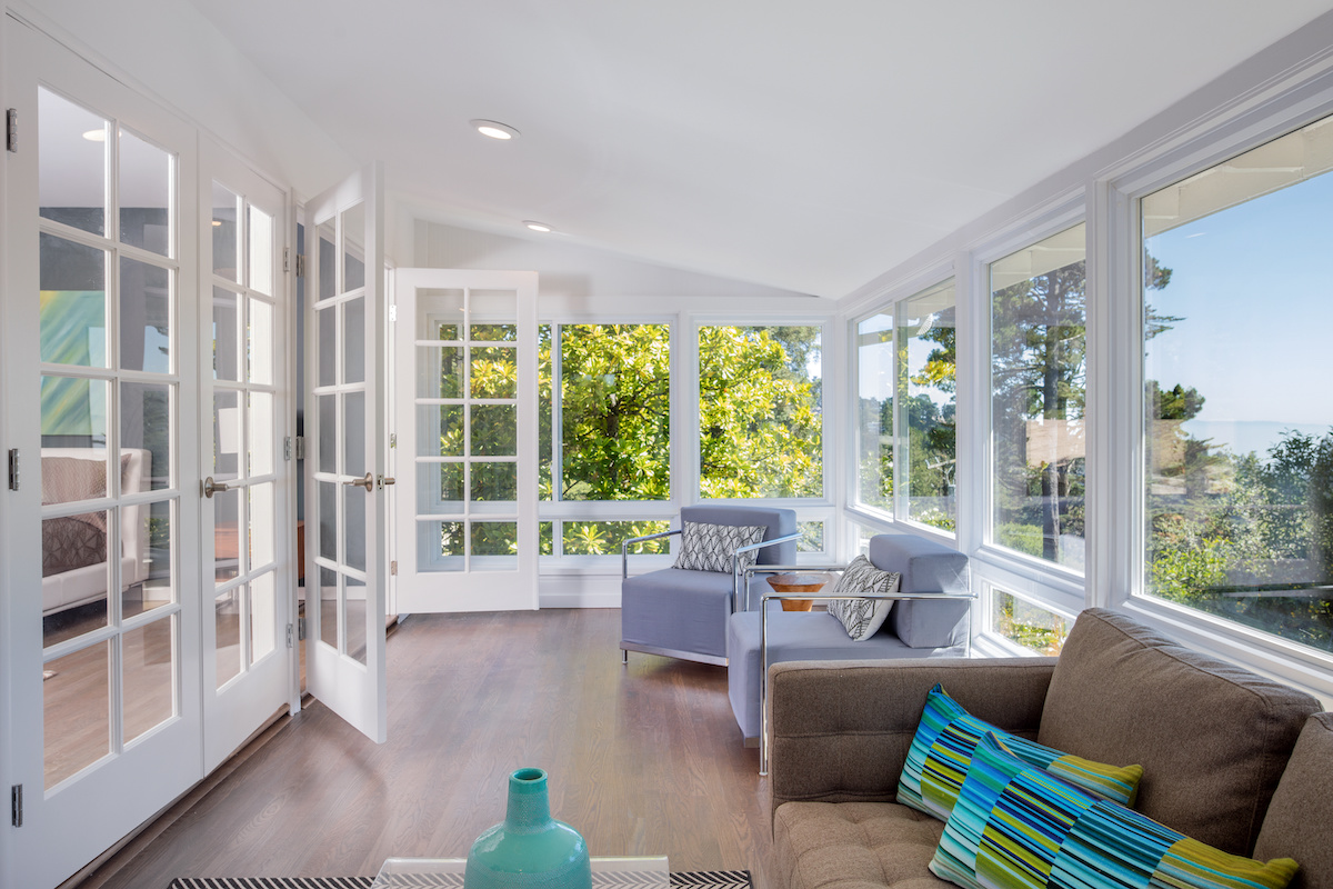 Bright sunroom with energy-efficient windows and French doors offering natural light and scenic outdoor view